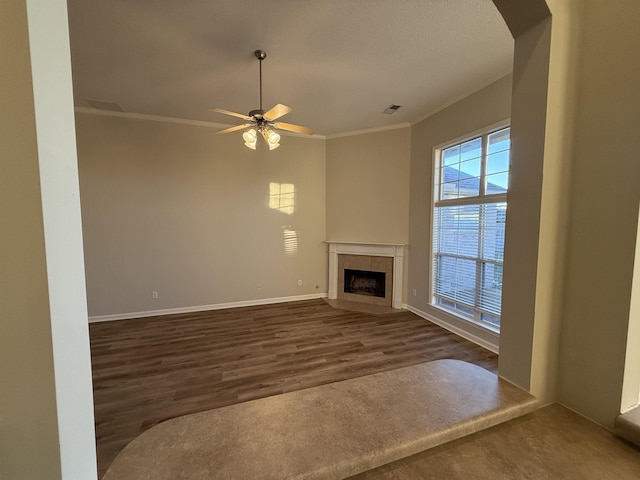 unfurnished living room featuring ceiling fan, ornamental molding, dark hardwood / wood-style flooring, and a tiled fireplace