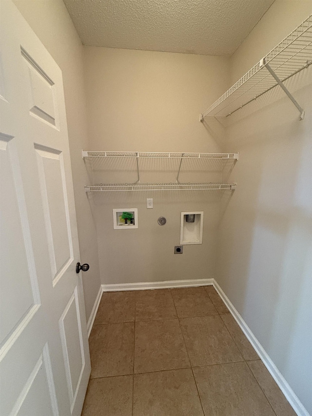 laundry room with dark tile patterned flooring, hookup for a gas dryer, hookup for a washing machine, hookup for an electric dryer, and a textured ceiling