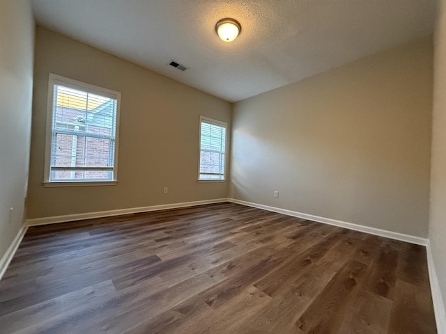 spare room featuring dark hardwood / wood-style flooring and a textured ceiling