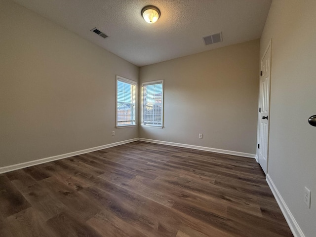 spare room featuring dark hardwood / wood-style floors and a textured ceiling