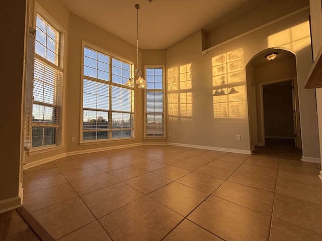 unfurnished dining area with tile patterned flooring and an inviting chandelier