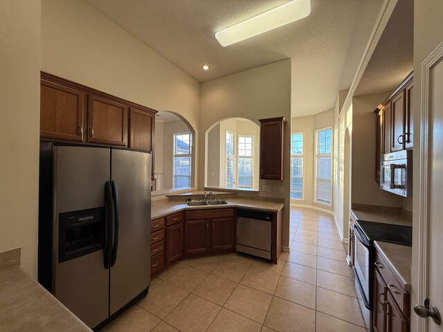 kitchen featuring sink, light tile patterned floors, stainless steel appliances, and a textured ceiling