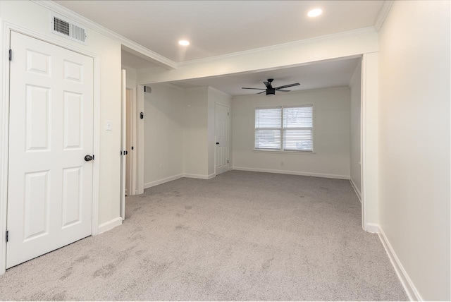 spare room featuring light carpet, crown molding, and ceiling fan