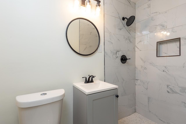bathroom featuring vanity, toilet, and tiled shower
