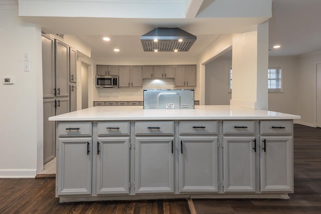 kitchen with dark wood-type flooring, gray cabinets, ornamental molding, and a center island