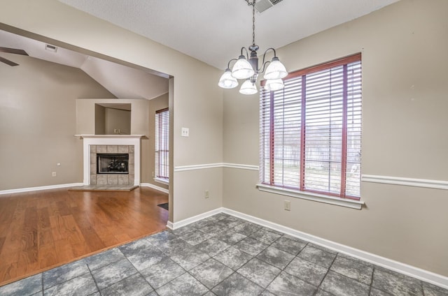 unfurnished dining area with vaulted ceiling, dark wood-type flooring, a chandelier, and a fireplace