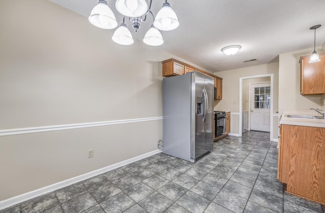 kitchen with sink, a textured ceiling, electric range, stainless steel fridge, and pendant lighting