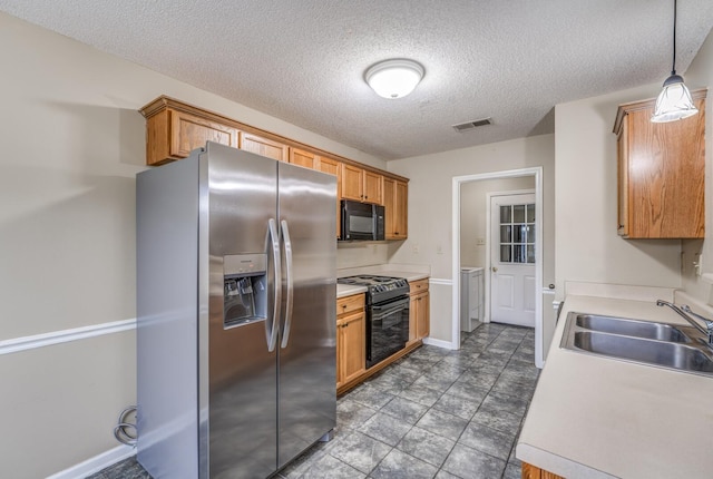 kitchen with sink, hanging light fixtures, black appliances, a textured ceiling, and separate washer and dryer