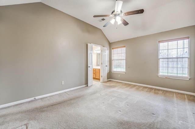 unfurnished bedroom featuring lofted ceiling, ensuite bath, light colored carpet, and ceiling fan