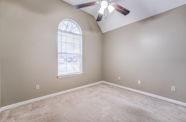 empty room featuring vaulted ceiling, light carpet, and ceiling fan