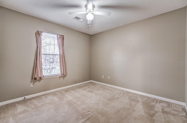 spare room with ceiling fan, light colored carpet, and a textured ceiling