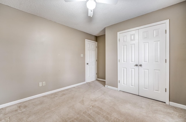 unfurnished bedroom with ceiling fan, light colored carpet, a textured ceiling, and a closet