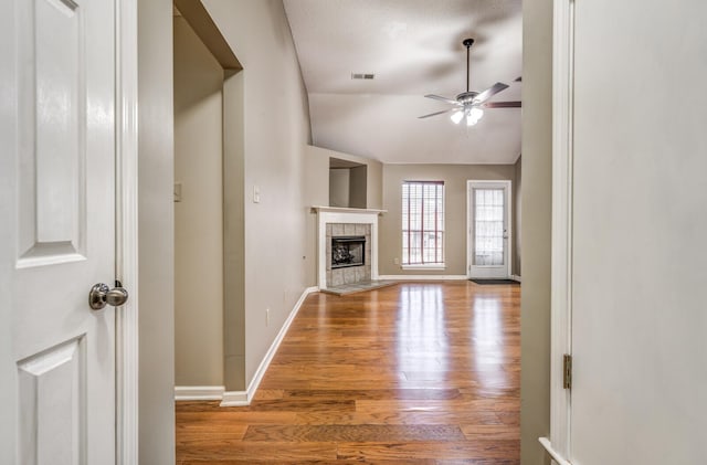 unfurnished living room with vaulted ceiling, ceiling fan, a fireplace, and light hardwood / wood-style flooring