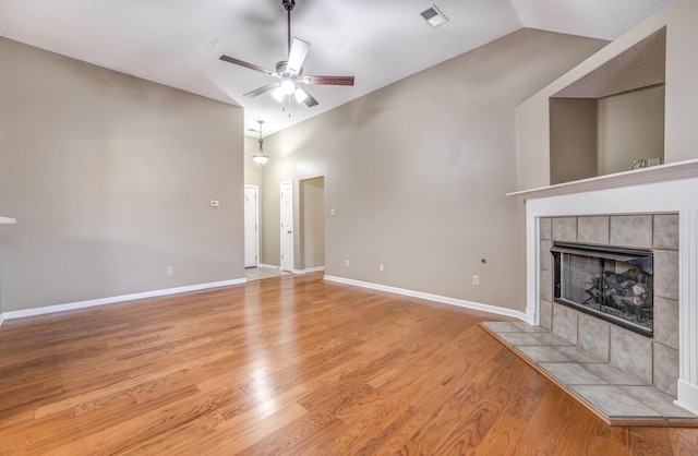 unfurnished living room featuring a tile fireplace, lofted ceiling, ceiling fan, and light hardwood / wood-style flooring