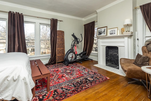 bedroom with multiple windows, ornamental molding, dark hardwood / wood-style flooring, and a fireplace