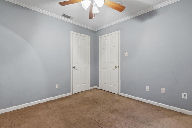 carpeted spare room with a textured ceiling, ornamental molding, and ceiling fan