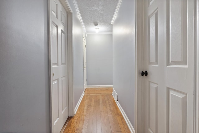 corridor with crown molding, a textured ceiling, and light wood-type flooring