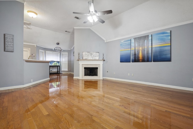 unfurnished living room with ceiling fan, lofted ceiling, hardwood / wood-style floors, and ornamental molding