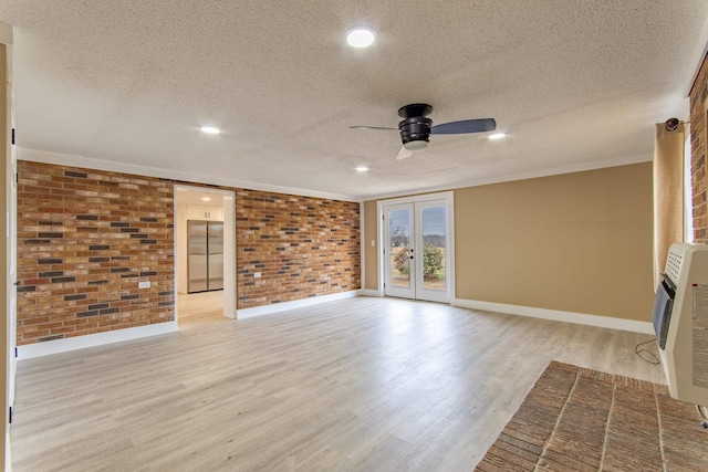 unfurnished living room with light hardwood / wood-style floors, french doors, a textured ceiling, and brick wall