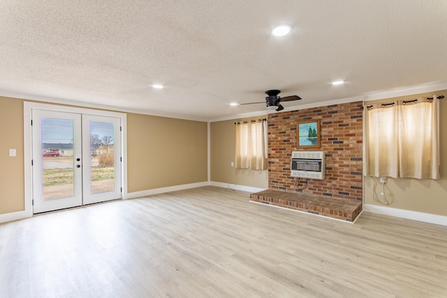 unfurnished living room featuring heating unit, a fireplace, light hardwood / wood-style flooring, a textured ceiling, and french doors