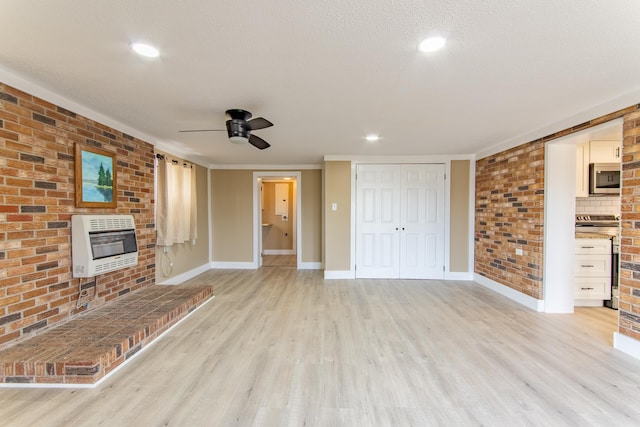 unfurnished living room featuring brick wall, heating unit, a textured ceiling, and light hardwood / wood-style floors