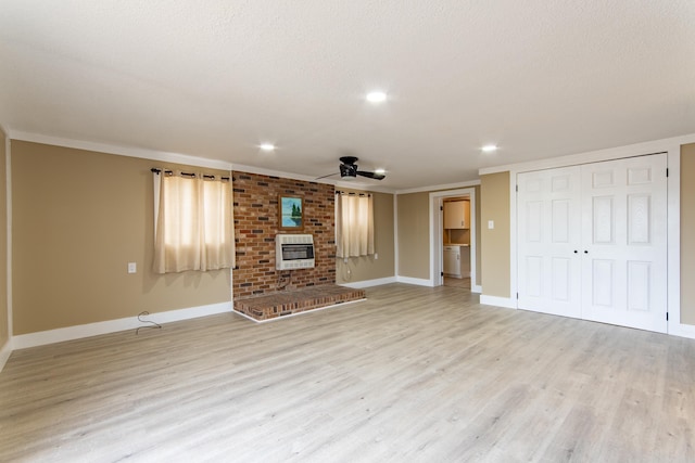 unfurnished living room featuring ornamental molding, a fireplace, heating unit, and light wood-type flooring