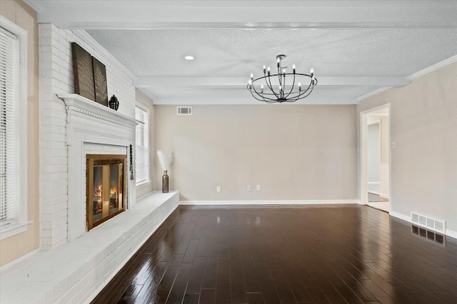 6961 Wittenham Cv, Memphis, TN 38119 - unfurnished living room with dark wood-type flooring, beamed ceiling, a textured ceiling, a brick fireplace, and a chandelier