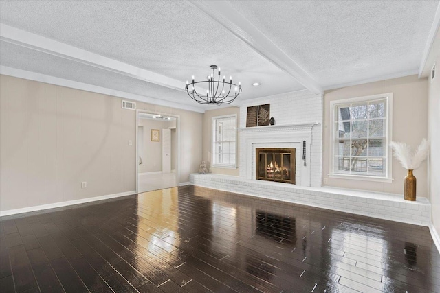 6961 Wittenham Cv, Memphis, TN 38119 - unfurnished living room with a chandelier, a brick fireplace, a textured ceiling, hardwood / wood-style flooring, and beam ceiling