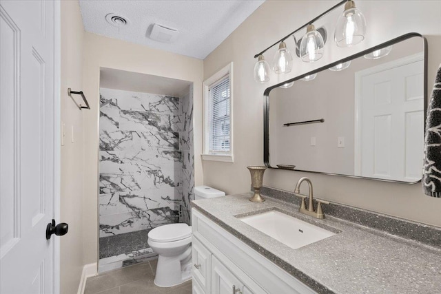 6961 Wittenham Cv, Memphis, TN 38119 - bathroom with a tile shower, vanity, a textured ceiling, tile patterned floors, and toilet