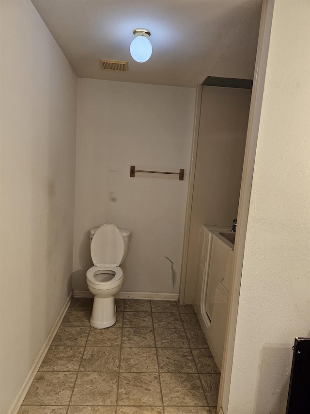 bathroom featuring washer / dryer and toilet