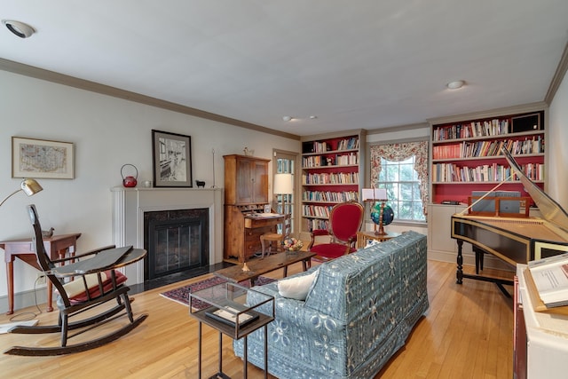 living room with crown molding, a high end fireplace, and light hardwood / wood-style floors