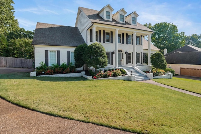 view of front of property featuring a garage, covered porch, and a front lawn