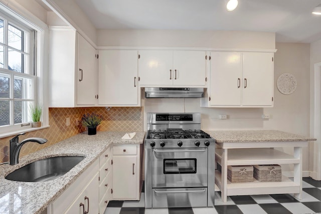 kitchen with stainless steel gas stove, sink, white cabinets, decorative backsplash, and light stone counters