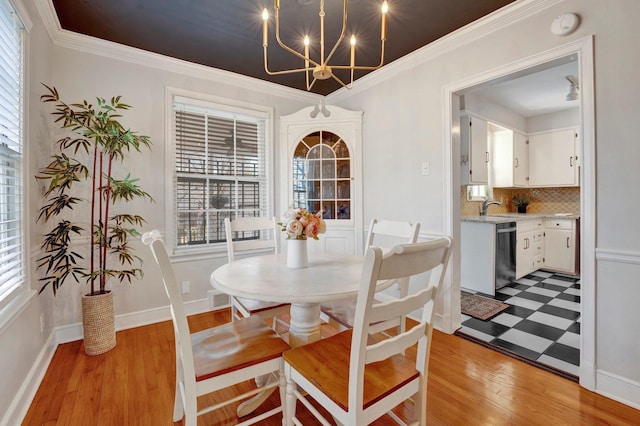 dining room featuring crown molding, an inviting chandelier, sink, and light hardwood / wood-style flooring