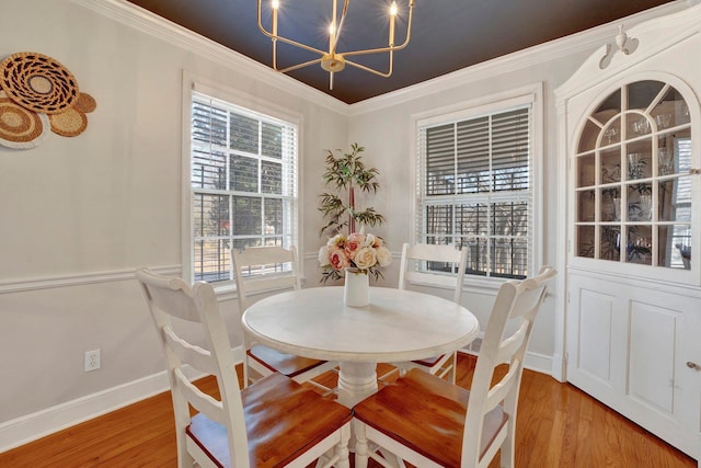 dining area with crown molding, a chandelier, and light wood-type flooring