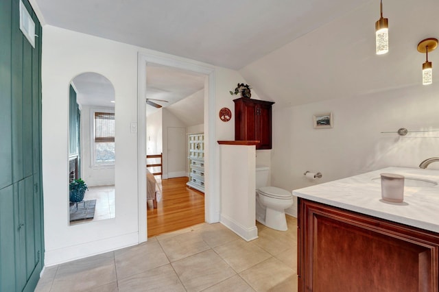 bathroom featuring lofted ceiling, tile patterned flooring, vanity, ceiling fan, and toilet