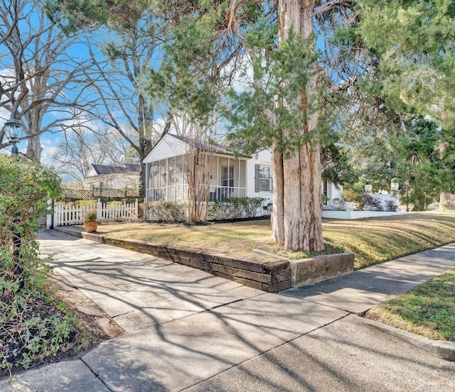 view of front of house featuring a sunroom and a front lawn