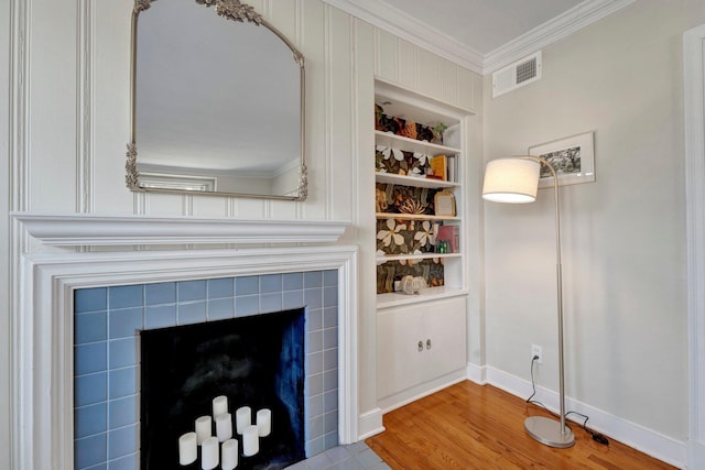 details with crown molding, a fireplace, built in shelves, and hardwood / wood-style floors