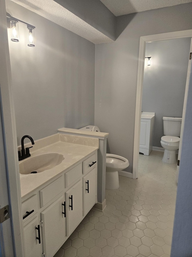 bathroom with vanity, a textured ceiling, tile patterned floors, and toilet