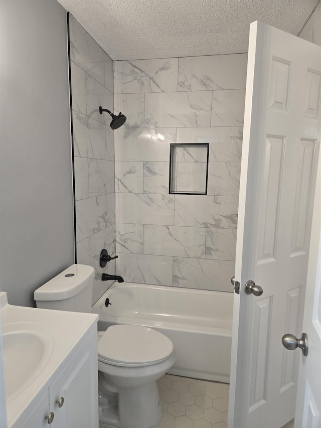 full bathroom with vanity, toilet, tiled shower / bath combo, and a textured ceiling