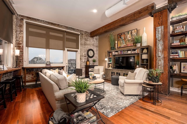 living room featuring brick wall, wood-type flooring, and beam ceiling