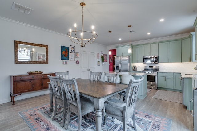 dining room with ornamental molding, sink, a notable chandelier, and light hardwood / wood-style flooring