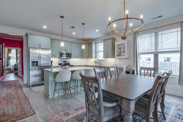 dining area with ornamental molding, light hardwood / wood-style floors, and a notable chandelier