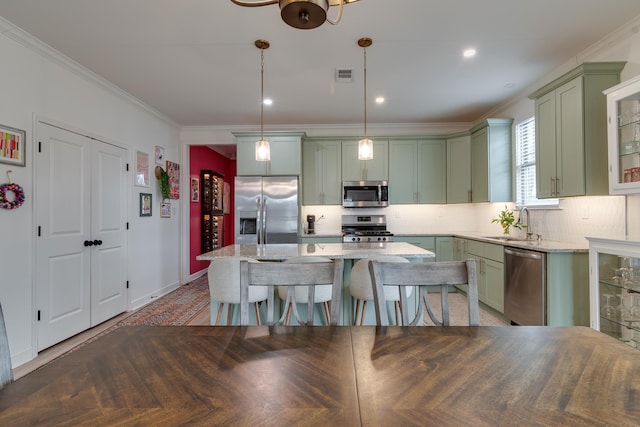 kitchen with stainless steel appliances, light stone countertops, a center island, and decorative light fixtures