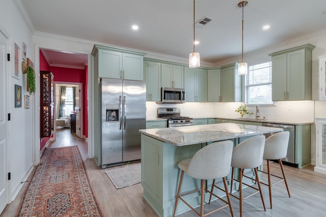 kitchen featuring sink, appliances with stainless steel finishes, hanging light fixtures, a center island, and light stone counters