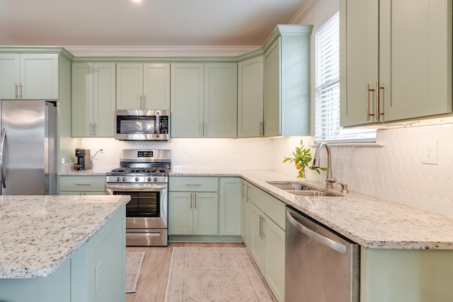 kitchen with light stone counters, sink, stainless steel appliances, and green cabinetry