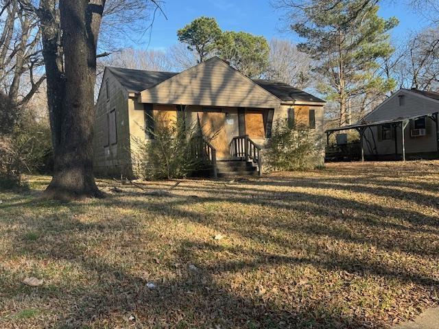 back of house featuring a carport and a lawn