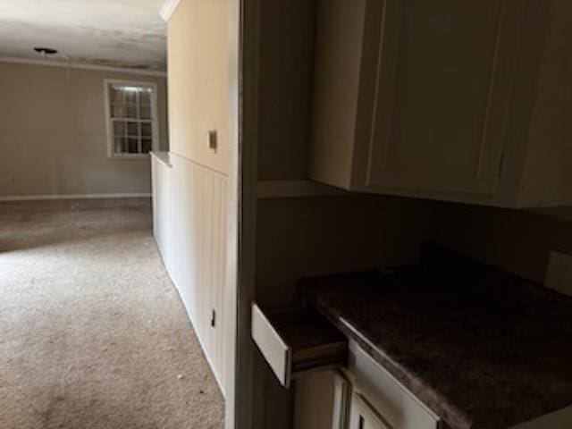 kitchen with crown molding and light carpet