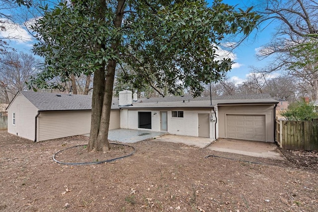 back of property with a garage and a patio