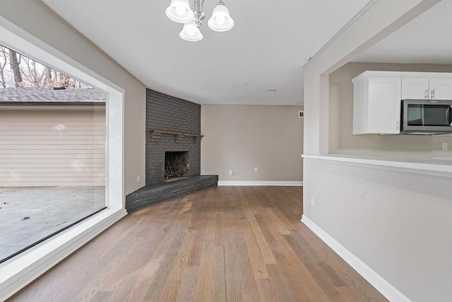 unfurnished living room featuring a fireplace, light hardwood / wood-style flooring, and a notable chandelier